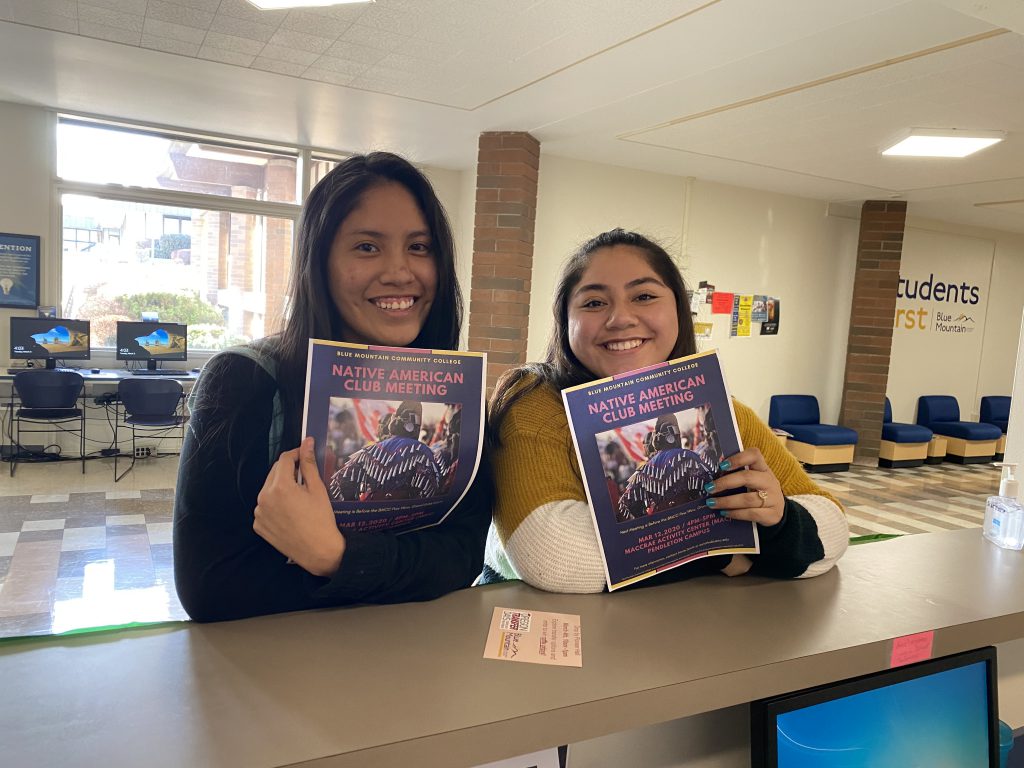 Two members of the Native American Club hold up club flyers.