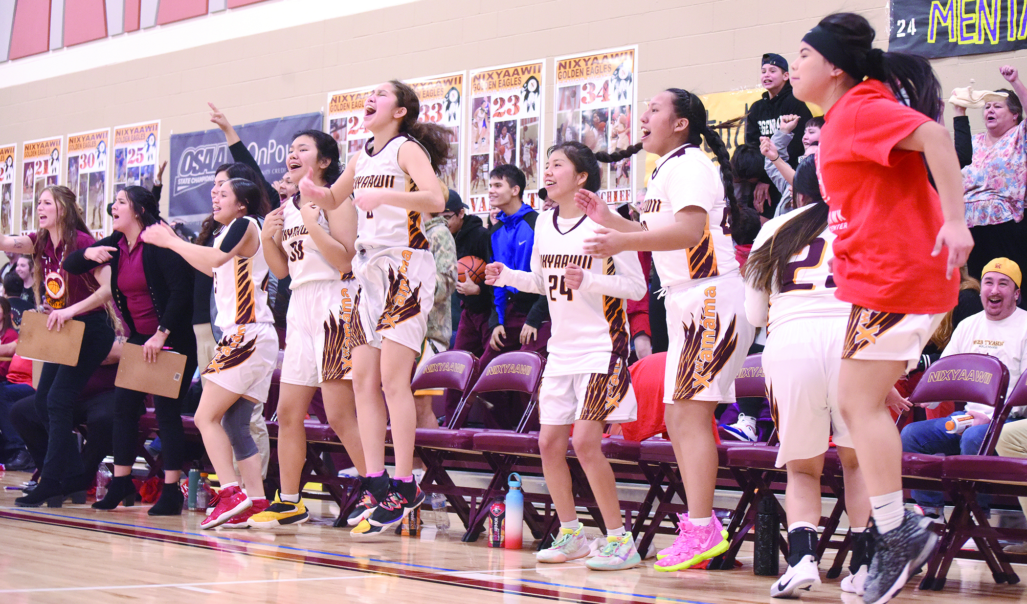 The bench was going crazy as the Nixyaawii girls mounted a comeback against Elgin in their next-to-last conference game. From left, the coaches and players included Coach Kaitlynn Melton, Coach Taryn Doiminguez, Ally Maddern (hidden), Ivory Herrera, Christina Kaltsukis, Adilia Hart, Mackenzie Kiona, Susie Patrick, Chelsea Farrow (back to camera), and Celia Farrow.