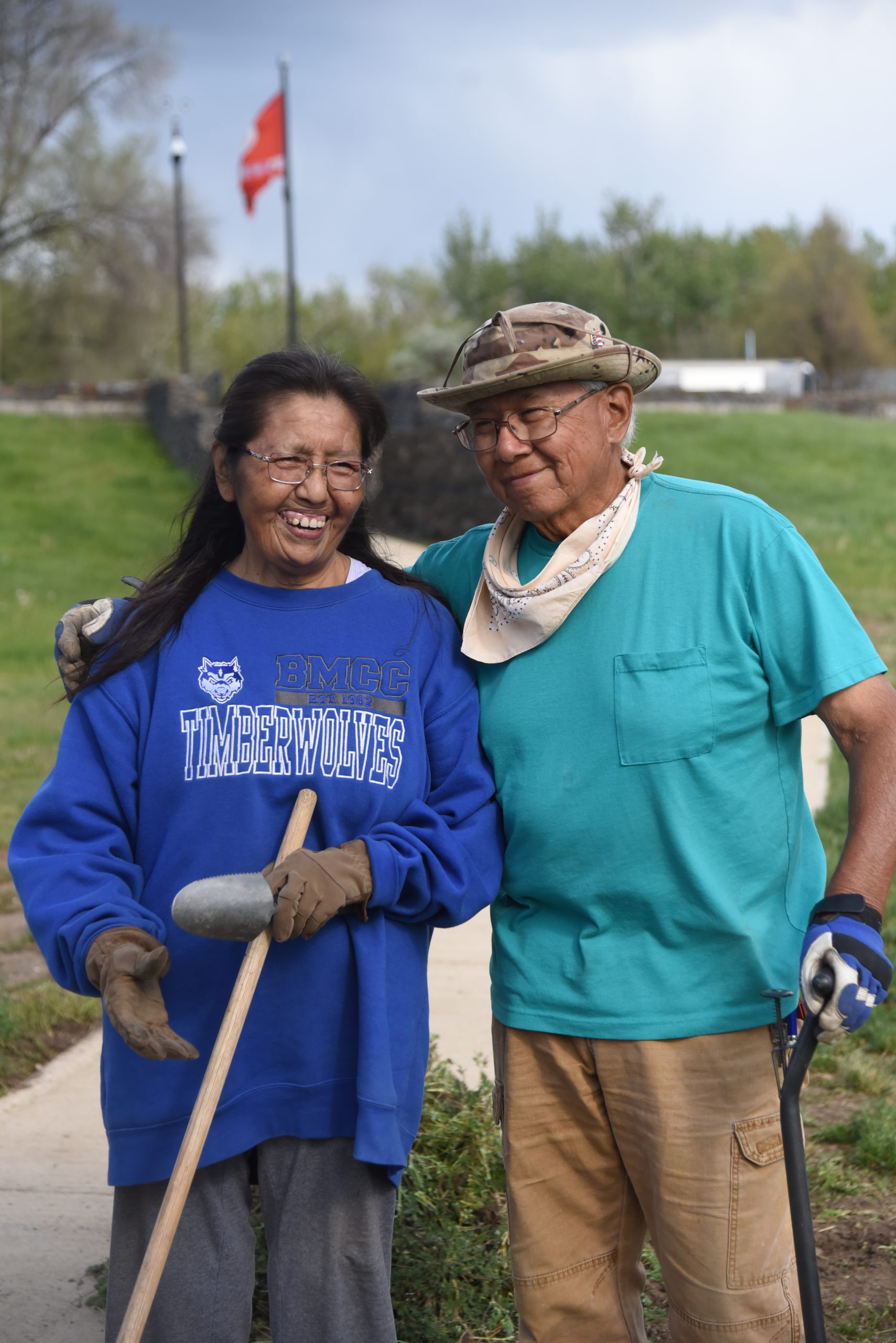 Retired couple with gardneing gear on stand before the Warriors Memorial.