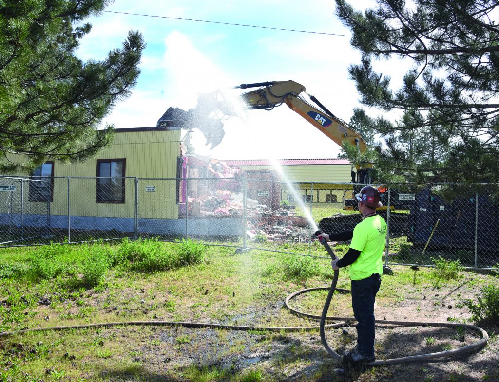 Wes Leers of Portland, who works for 3 Kings Environmental from Battle Ground, Washington, sprays water on the former accounting office for Yellowhawk Tribal Health Center. That building and several more, including the old clinic and Cay-Uma-Wa Education facility, are being razed over the next eight weeks. That will leave the July Grounds mostly empty except for the Community Center, the Longhouse and a couple of other smaller buildings.
