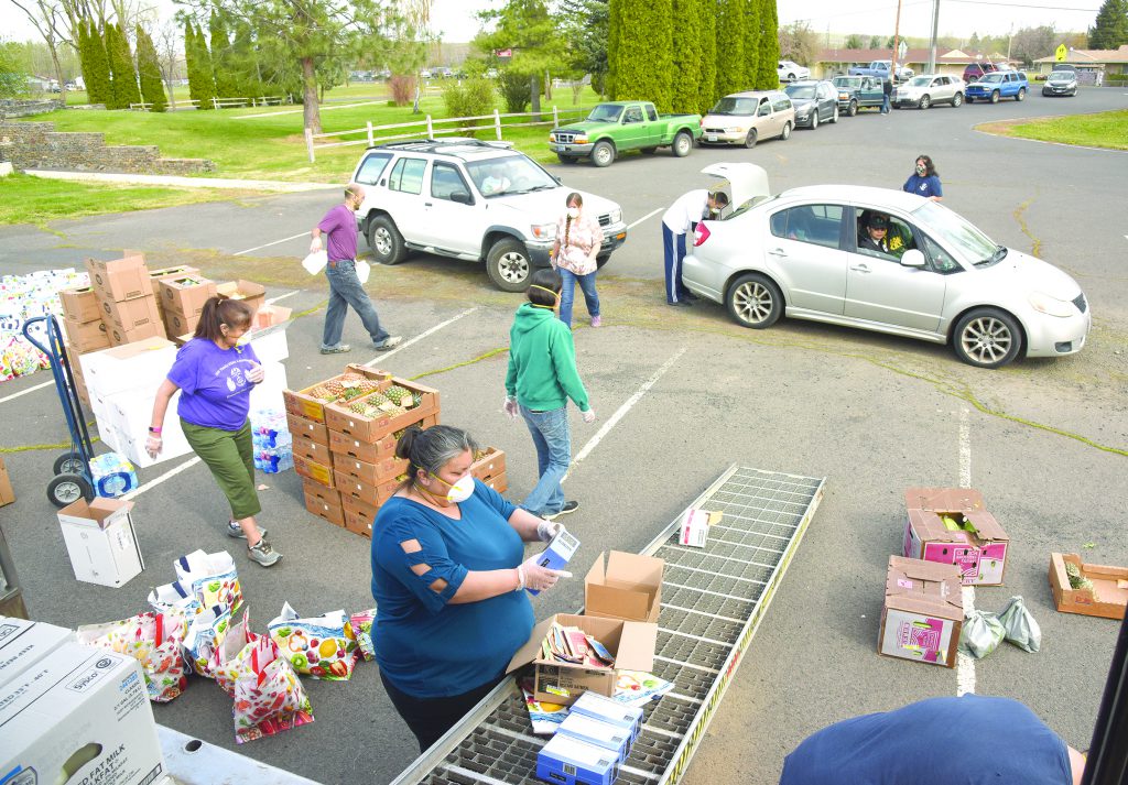 Staff from CTUIR departments and programs, as well as many volunteers, handed out food to hundreds of tribal members and others who reside on the Umatilla Indian Reservation during first-come, first-served distributions April 18 and May 1. In addition to the menu listed below, elders received hamburger patties and a half gallon of milk; families received half a roasted chicken and a chub of ground beef. Other items that were purchased or donated for the distribution included celery, a whole pineapple, sliced turkey, mixed berry yogurt, fruit mix, flour tortillas, bread, hot instant cereal and a bag of plastic resealable bags. Julie Taylor, director of the Department of Children and Family Services, who stands on the other side of the silver car, organized the event.