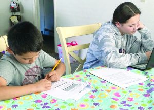 Two kids sit at the dinner table and work on homework.