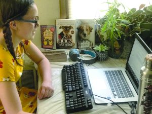 Girl does schoolwork on her computer.