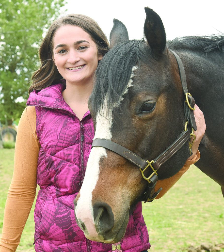 Teenager stands with her horse.