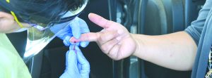 Nurse draws blood from a patient's finger.